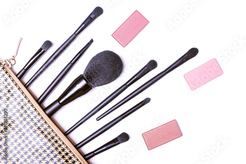 Fototapeta Naklejka Na Ścianę i Meble -  Makeup brushes and decorative cosmetics spilling out over a white background, top view.