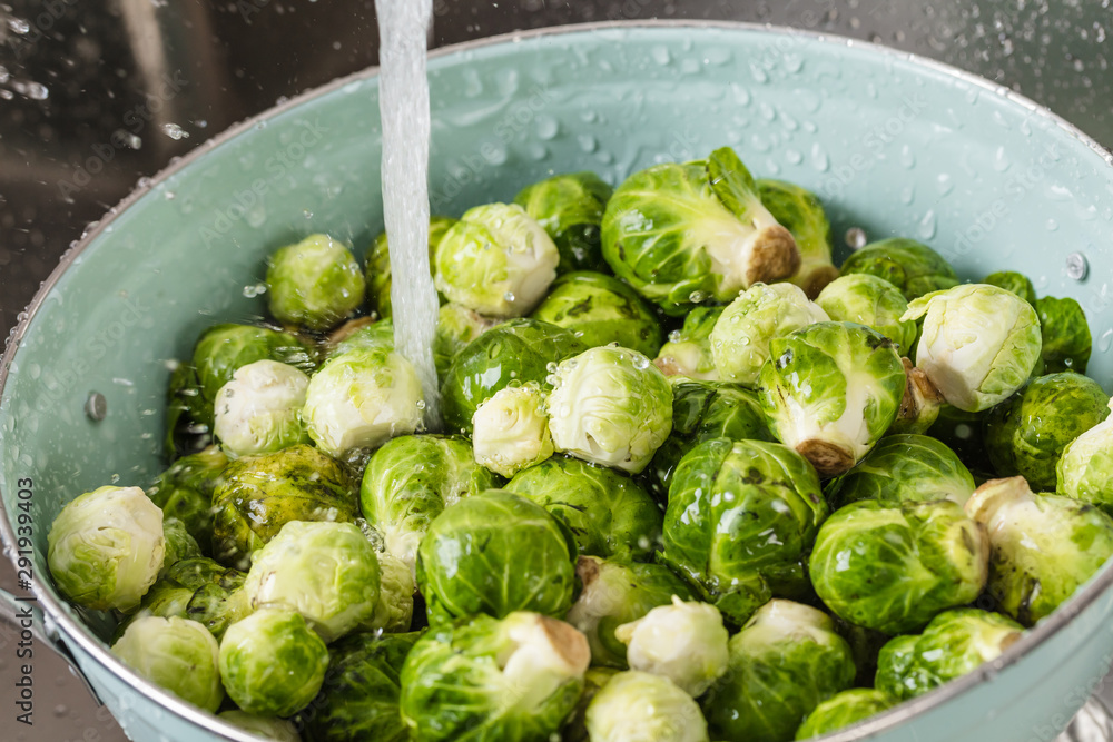 washing raw Brussels sprouts in kitchen sink washing raw Brussels sprouts in kitchen sink