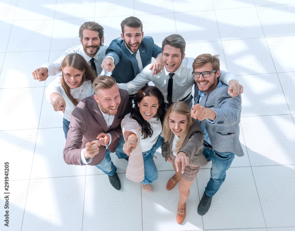 top view. a group of smiling young business people pointing at you.