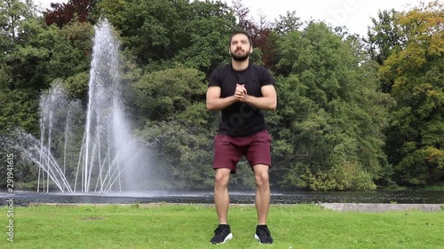 Man doing squats in park near fountain