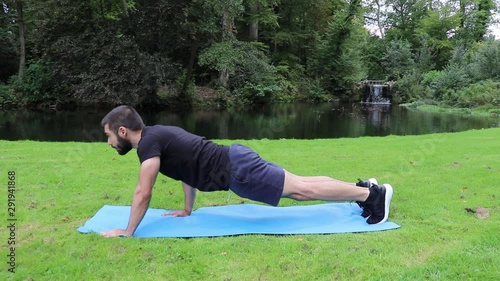 Man staggered push ups in park