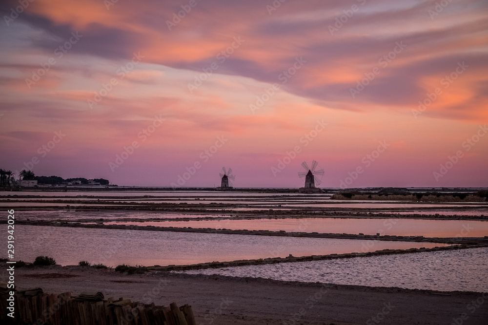 Sunset .Shallow salt pools and windmills Trapani Sicily .The salt from these marshes is considered Italy’s finest and has been big business for centuries; today, only a cottage industry remains