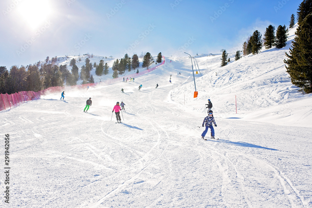 Happy people, children and adults, skiing on a sunny day in Tyrol mountains