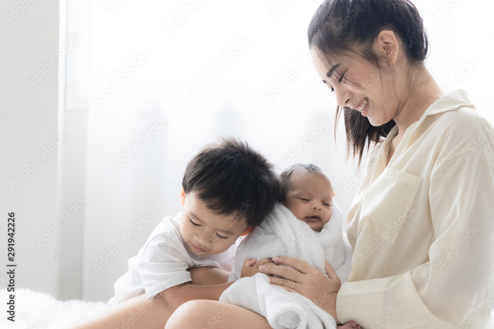 Asian young mother with cute newborn baby and the son in bed. Happy family and mother 's day concept. Asian young mother with cute newborn baby and the son in bed. Happy family and mother 's day concept.