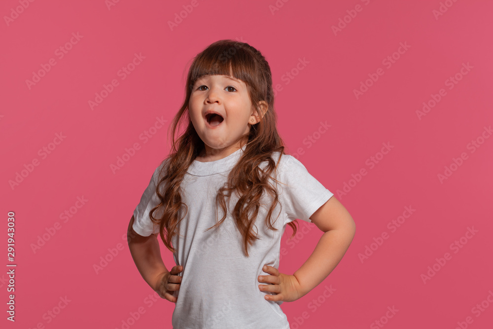 Close-up portrait of a little brunette girl dressed in a white t-shirt posing against a pink studio background. Sincere emotions concept. Close-up portrait of a little brunette girl dressed in a white t-shirt posing against a pink studio background. Sincere emotions concept.