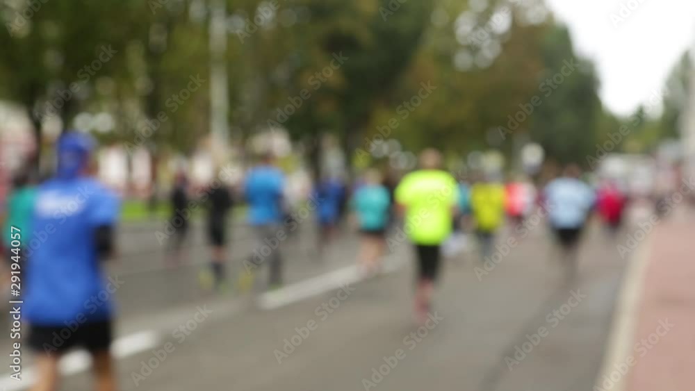 Closeup view of many blurry silhouettes of people running outdoors by city streets during charity marathon. Closeup view of many blurry silhouettes of people running outdoors by city streets during charity marathon.