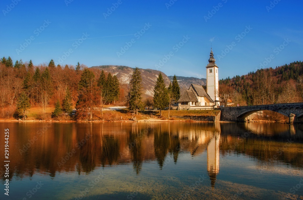 Autumn reflections on lake Bohinj, Julian Alps, the largest permanent lake in Slovenia and the Church of St. John the Baptist.