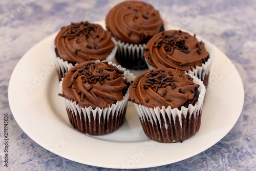 Chocolate cupcakes over white plate and blue blurred background