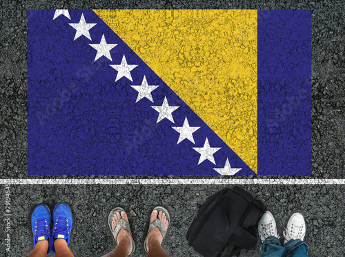 Photography people legs is standing on asphalt road  next to flag of Bosnia and Herzegovina
