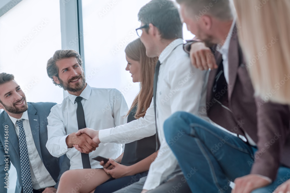 Obraz premium young business people shaking hands while sitting in the office lobby