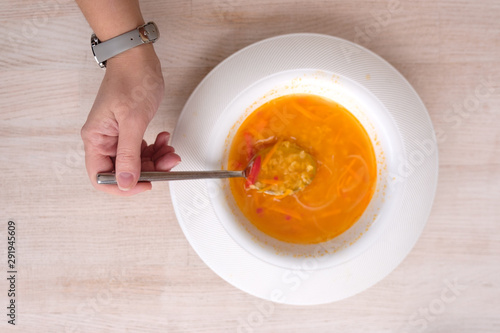 bright orange soup in a white plate.top view