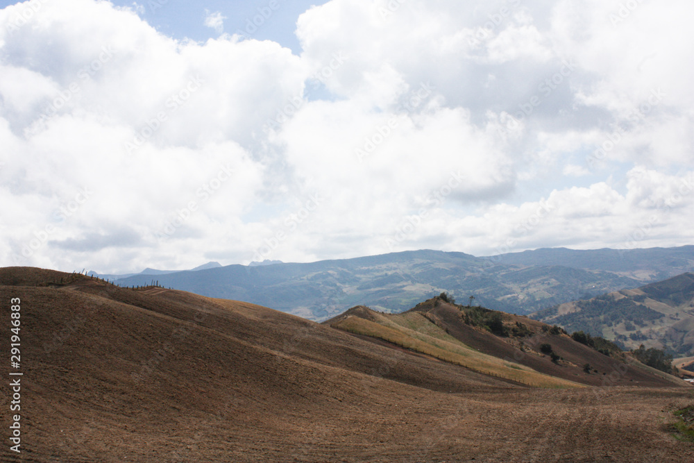 Obraz premium Landscape of colombian mountains with Andes Mountain Rage, whith crops. Blue sky with clouds. Rock hills