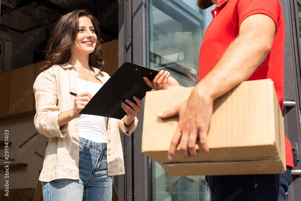 cropped view of delivery man holding box near attractive girl with clipboard cropped view of delivery man holding box near attractive girl with clipboard