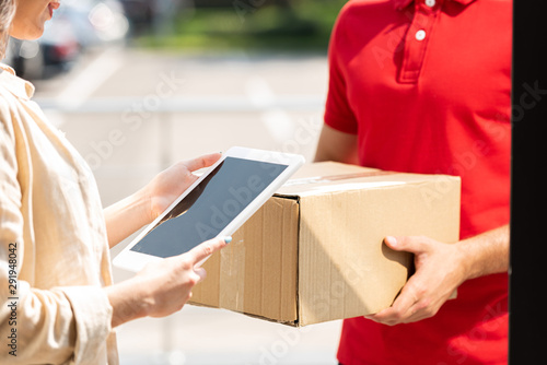 cropped view of delivery man holding box near woman with digital tablet © LIGHTFIELD STUDIOS