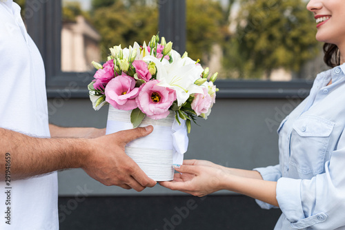 Принти на полотні cropped view smiling girl receiving flowers from delivery man outside
