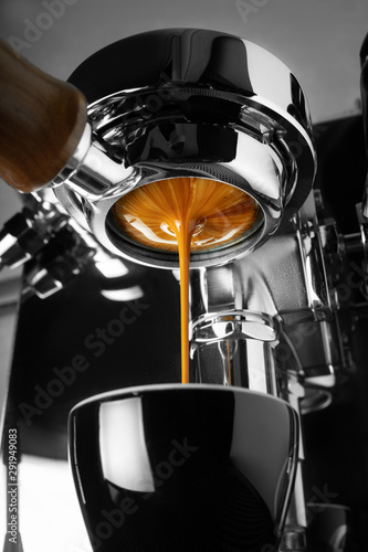 A coffee machine is preparing a cup of espresso. Blurred background.