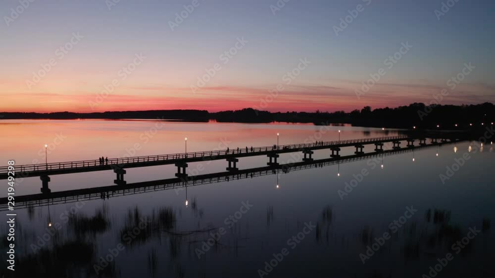 Drone Flight at Sunset by the lake Sirvena in Birzai - the longest wooden bridge in Lithuania.The bridge is located in Regional Park, connecting Birzai with Astravas Manor on the northern edge of the Drone Flight at Sunset by the lake Sirvena in Birzai - the longest wooden bridge in Lithuania.The bridge is located in Regional Park, connecting Birzai with Astravas Manor on the northern edge of the