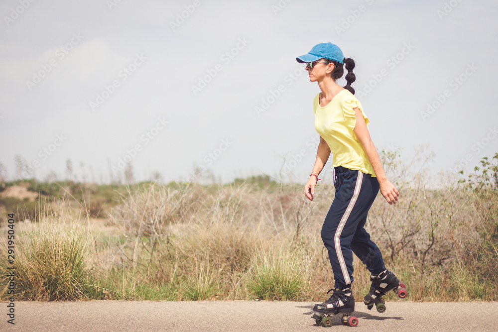 Fototapeta premium Woman skating on a lonely road in the desert