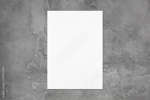 Empty white vertical rectangle poster mockup with soft shadow on dark grey concrete wall background. Flat lay, top view