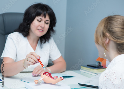 Slika na platnu a woman in a white coat and blue gloves, a gynecologist sits at a table and cond