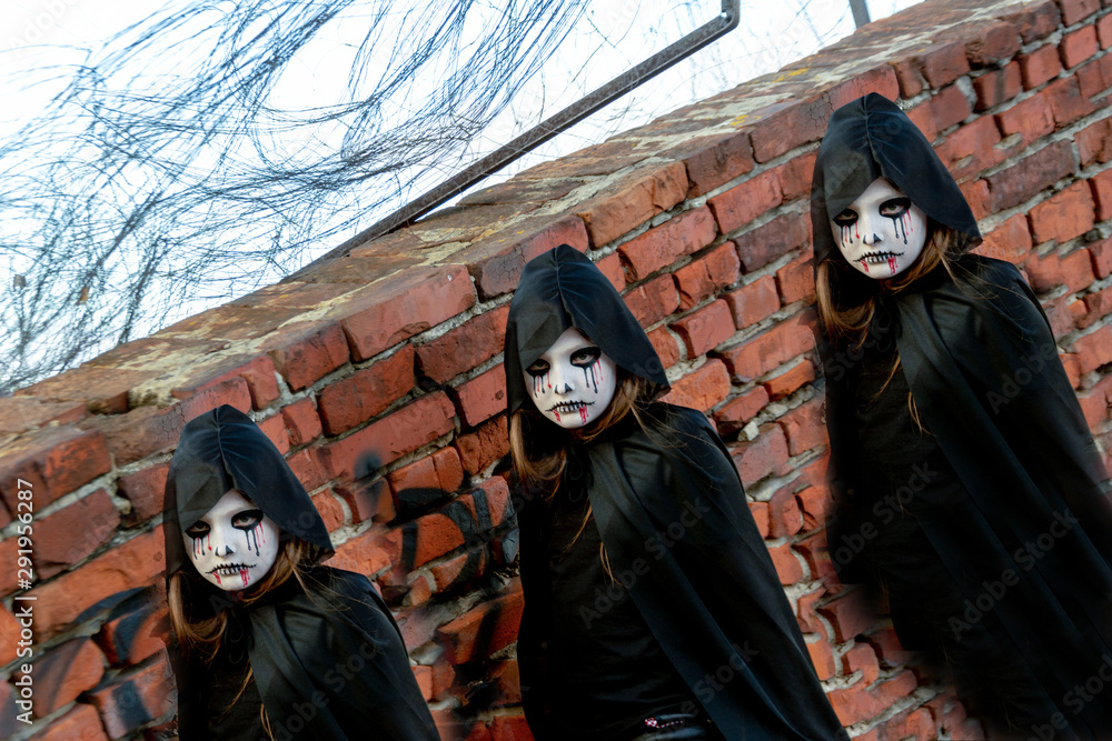 Portrait of a little teenager girl in a zombie costum against a brick wall. Halloween and day of the dead concept. Zombie looks at the camera intimidatingly Portrait of a little teenager girl in a zombie costum against a brick wall. Halloween and day of the dead concept. Zombie looks at the camera intimidatingly
