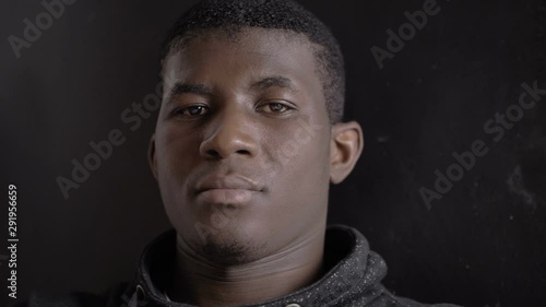 serious confident young american african man straing at camera in the dark photo