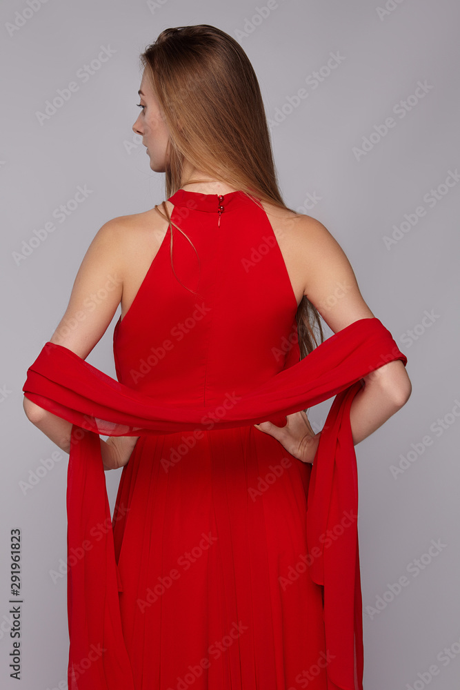 Medium back shot of young blonde European lady with long straight hair in a  fire-red