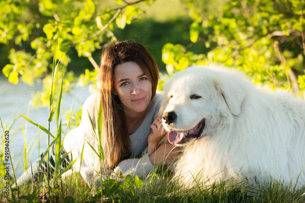 A lovely girl and Cute maremma sheepdog. Big white happy dog breed maremmano abruzzese lying in the forest in summer A lovely girl and Cute maremma sheepdog. Big white happy dog breed maremmano abruzzese lying in the forest in summer