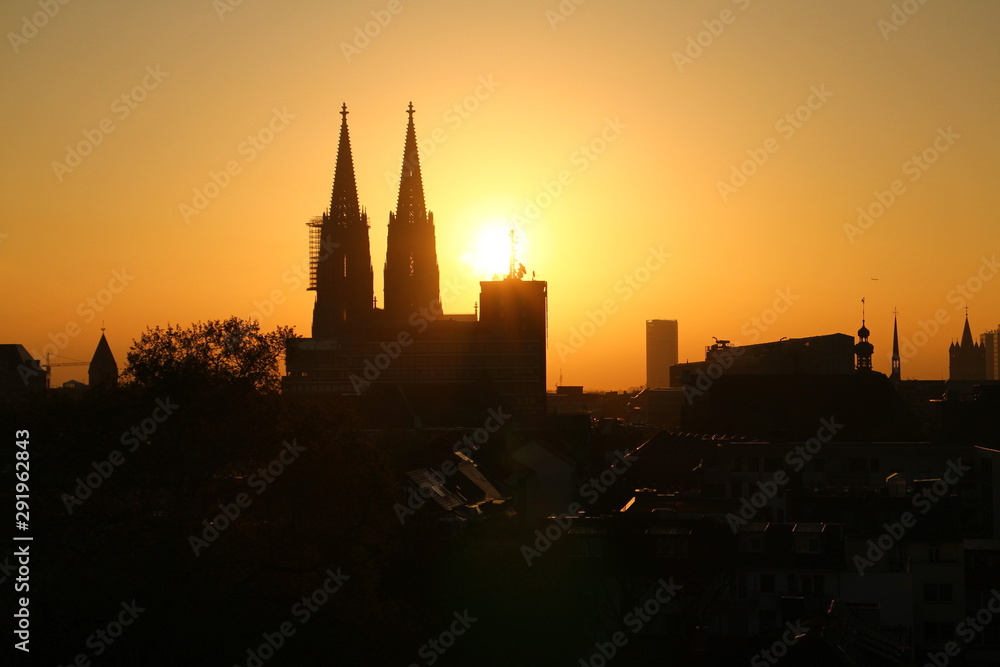 Early morning view over the historical part of Cologne, Germany. Silhouette of Cologne Cathedral (German: Kölner Dom). Bright orange sunrise.