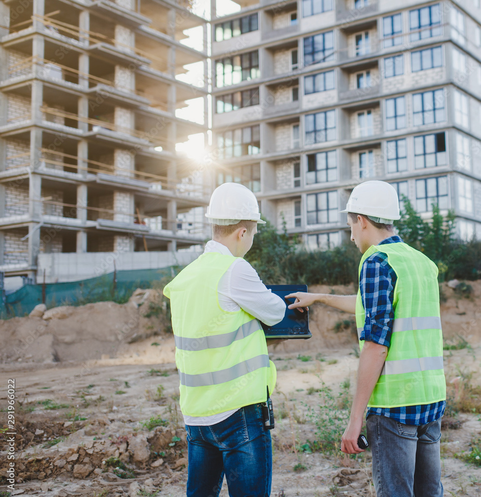 two construction engineers with laptop on construction site two construction engineers with laptop on construction site