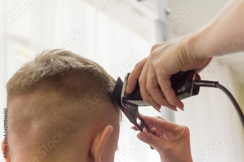 the Barber cutting the boy trimmer head teen almost bald