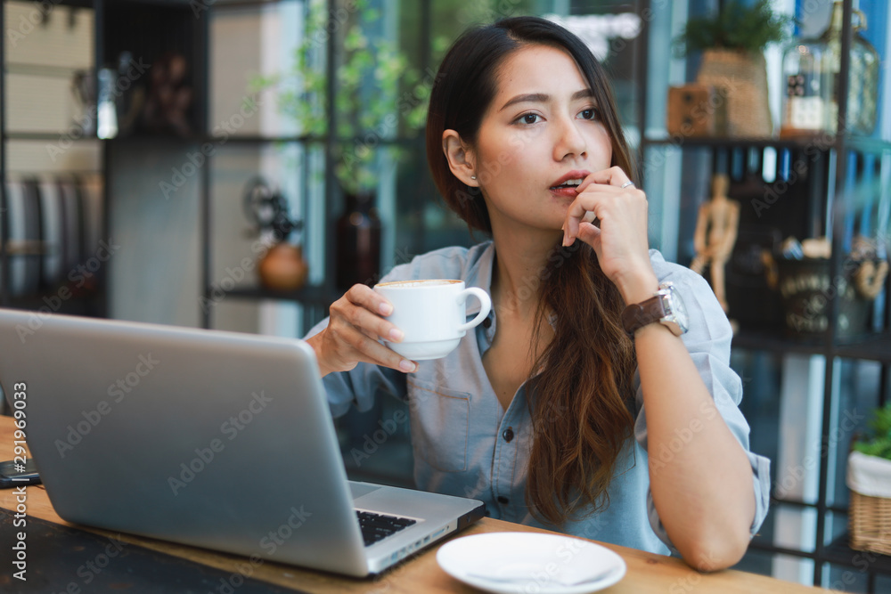 Asian woman in blue shirt working and drink coffee in coffee shop cafe vintage color tone Asian woman in blue shirt working and drink coffee in coffee shop cafe vintage color tone