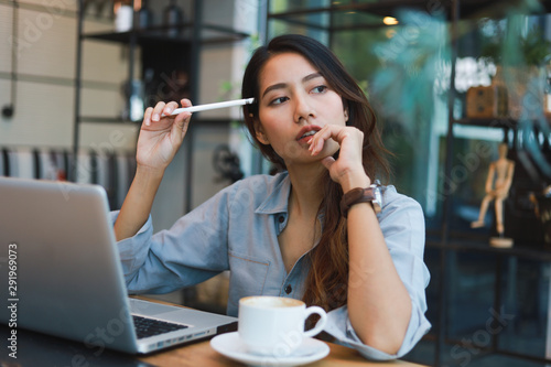 Asian woman in blue shirt working and drink coffee in coffee shop cafe vintage color tone