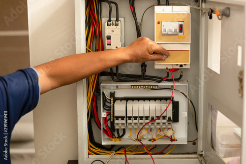 Senior electrician measuring voltage in fuse board.