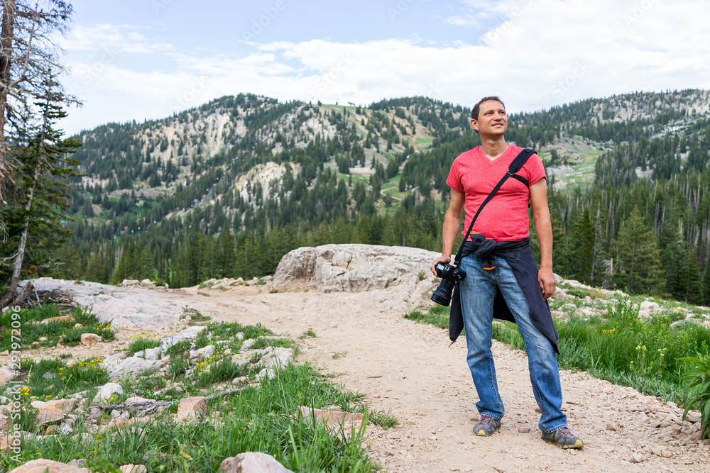 Naklejka premium Albion Basin, Utah summer with rocky trail view in Wasatch mountains with man tourist standing on road to Cecret Lake and wildflowers