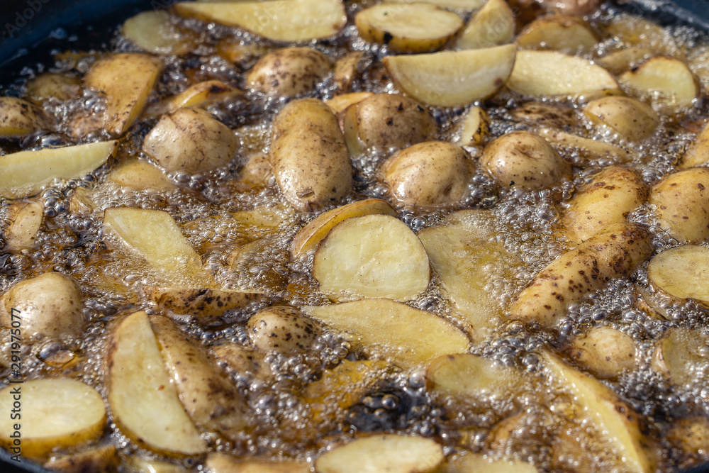 Roast potatoes in a large pan.Young potatoes are fried in oil, street food Roast potatoes in a large pan.Young potatoes are fried in oil, street food
