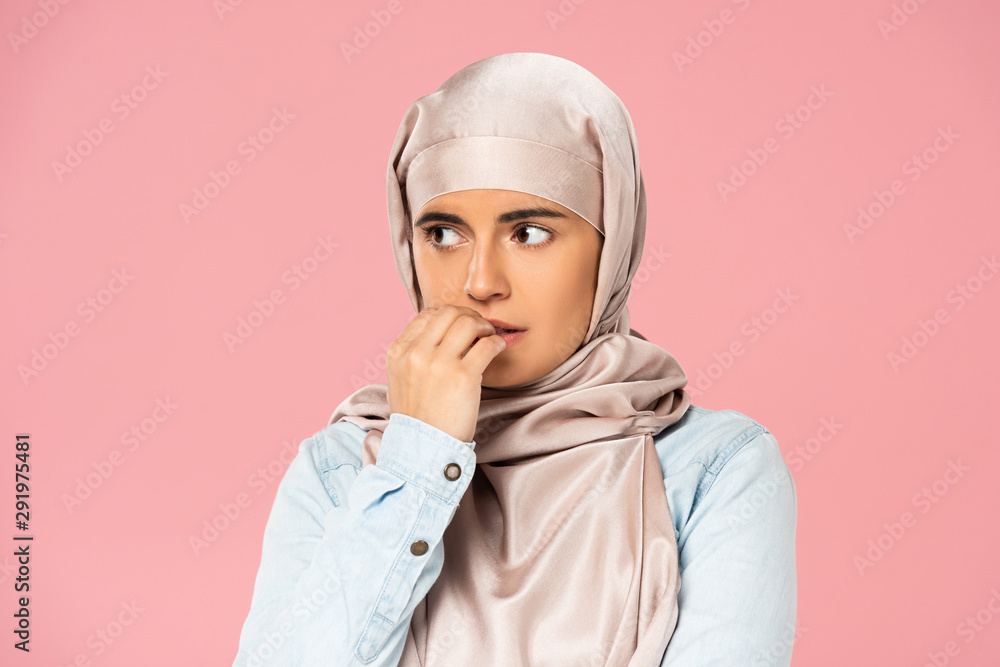 scared muslim girl in hijab biting nails, isolated on pink scared muslim girl in hijab biting nails, isolated on pink