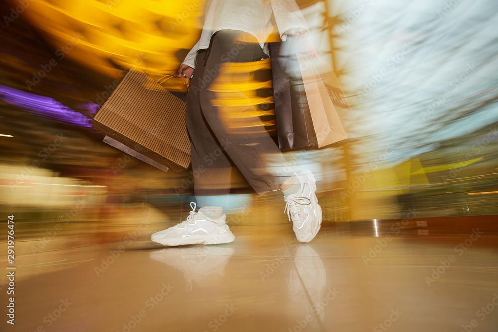 Fototapeta premium Blurred motion of woman standing with paper bags in the shop