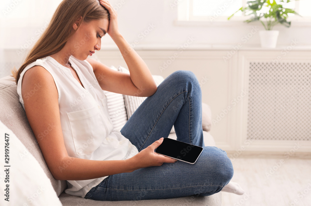 Sad Girl Holding Cellphone Sitting On Couch At Home