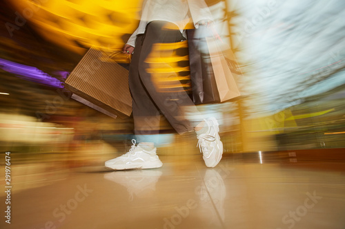Blurred motion of woman standing with paper bags in the shop photo