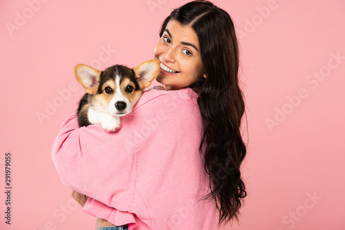 beautiful woman holding Welsh Corgi puppy, isolated on pink