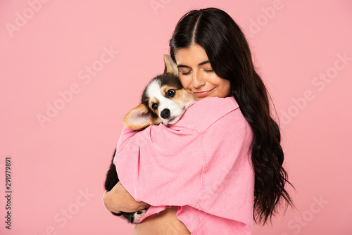 happy woman hugging Welsh Corgi puppy, isolated on pink