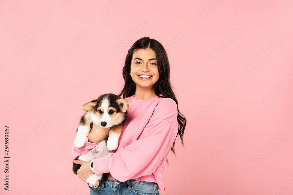 smiling woman holding Welsh Corgi puppy, isolated on pink smiling woman holding Welsh Corgi puppy, isolated on pink