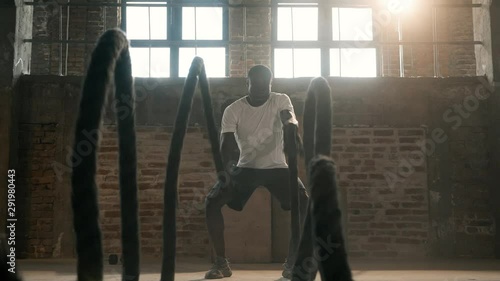 Rope workout. Sport man doing battle ropes exercise at gym