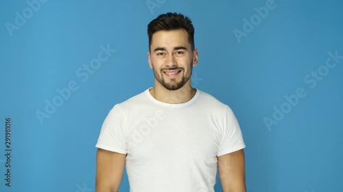 Athletic guy in white t-shirt smiling on blue background. Close up