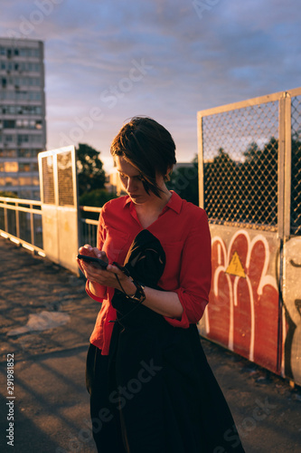 woman with phones in hand dials the number during sunset photo