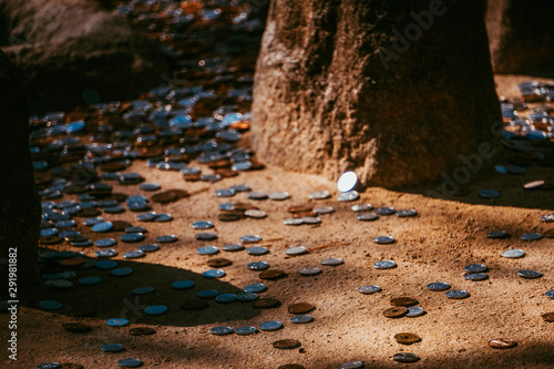 Money on the floor. Someone throw or dropped coins on the ground. Dirty coins next to the rock. One coin is shining under the sun.