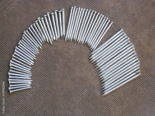 puntas, clavos de distintos tamaños, para clavar y hacer obras en casa, do it yourself, colocadas en forma de arco sobre tela gris photo