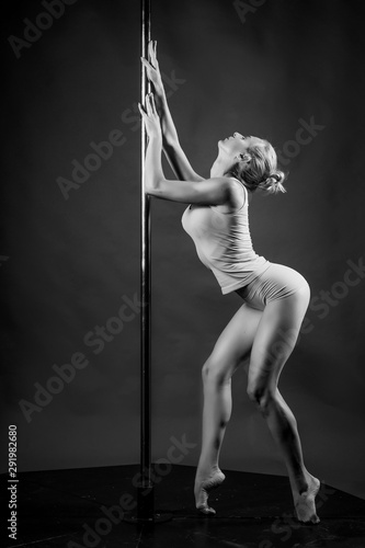 Obraz na plátně Beautiful athletic busty elegant blonde girl performs artistic elements of an exotic dance on a gray background