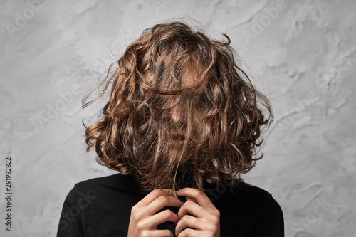 Fotografi Closeup portrait of young lady with disheveled hair covering her face